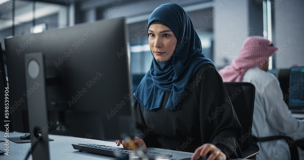 Poster Young Arab Female Artificial Intelligence Engineer Working on Computer in a Technological Office. Young Middle Eastern Specialist Writing Software Code for an Innovative Big Data Blockchain Project