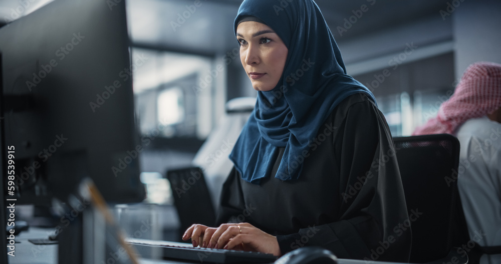 Poster Portrait of a Smart Focused Middle Eastern Engineer Working on Computer in a Technological Corporate Office. Young Arab Woman Developing Software for an Innovative Internet Service Provider