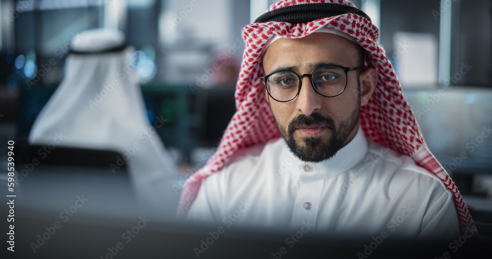 Poster Portrait of a Thoughtful Middle Eastern Engineer Working on Computer in a Technological Corporate Office. Manager Working with Colleagues on Innovative Internet and Software as a Service Project