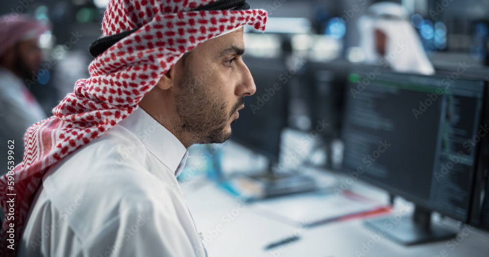 Poster Portrait of a Middle Eastern Engineer Working on Desktop Computer in a Technological Office Environment. Arab Software Developer Researching New Ideas to Problem Solve a Technical Assignment