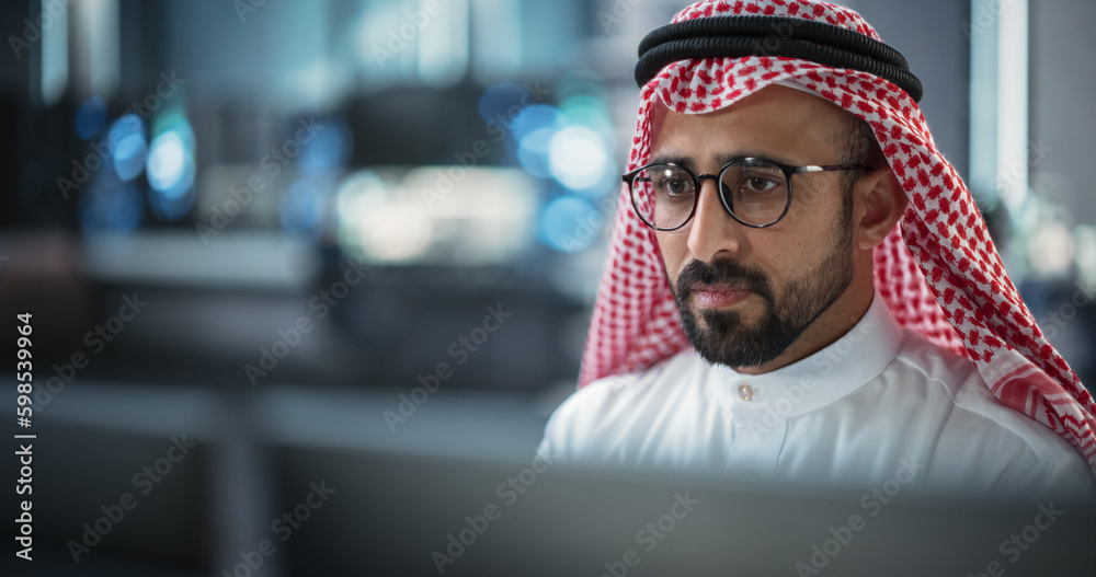 Aufkleber Portrait of a Middle Eastern Engineer Working on Desktop Computer in a Technological Office Environment. Muslim Specialist in Glasses Wearing Traditional Thobe and Kaffiyeh in Agency