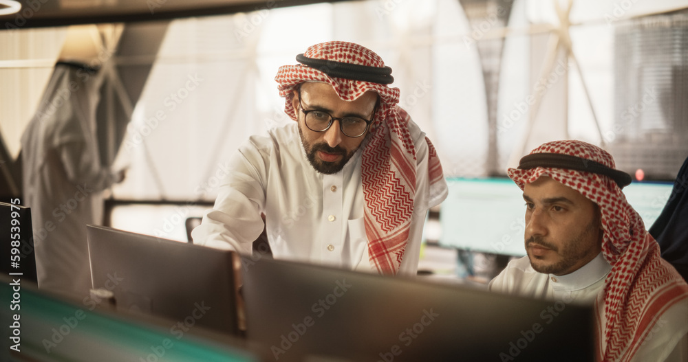Poster Arab Graphic Designer Working on Computer, Discussing Project with Team Leader. Middle Eastern Colleagues Working in Modern Office, Wearing Traditional White Thobes and Kaffiyeh