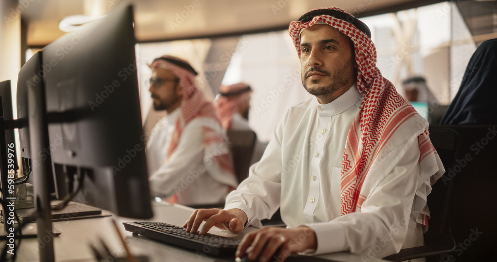 Aufkleber Portrait of a Middle Eastern Financial Securities Trader Working on Desktop Computer in a Modern Office. Arab Bookkeeper Accounting the Financial Affairs of a Business