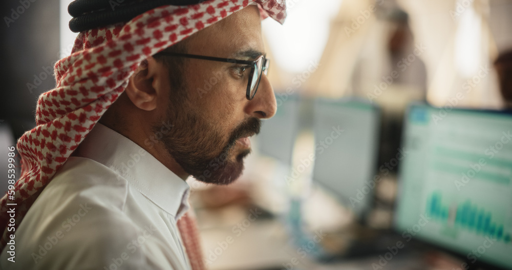 Aufkleber Portrait of a Middle Eastern Financial Securities Trader Working on Desktop Computer in a Modern Office. Arab Bookkeeper Accounting the Financial Affairs of a Business