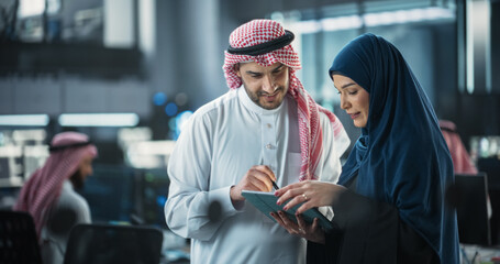 Team of Two Diverse Specialists Use Tablet Computer. Having a Conversation on a Cybersecurity Project. Empowered Young Middle Eastern Male and Female Work on Digital E-Commerce Startup Business