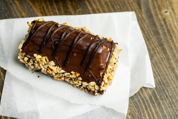 Fresh sweet cake with banana in chocolate glaze and milk filling