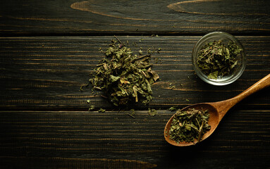 Dry green herbs in a wooden spoon and on a vintage table before making a medicinal tea. Traditional medicine concept
