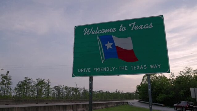 Welcome to Texas - drive friendly the Texas way sign on the state line with gimbal video stable showing vehicles.