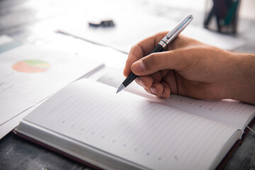 Man writing in a notebook in front of statistics