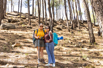 Two senior women hiking on mountain, walking through forest