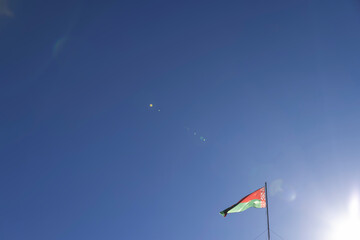 The national flag of the Republic of Belarus in windy weather against the blue sky