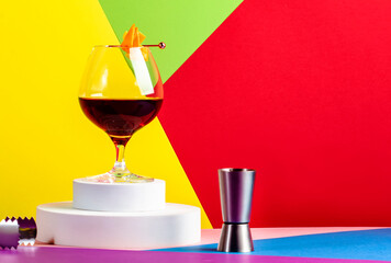 Martinique cocktail drink with golden rum, red vermouth, liqueur, bitter and orange zest. Modern style still life on creative bright multi-colored background