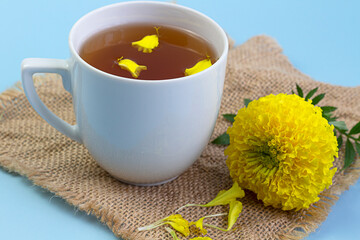 Marigold herbal tea in a glass cup fresh flowers on sackcloth