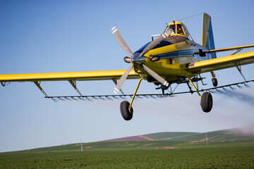 Fototapeta na wymiar Close up image of crop duster airplane spraying grain crops on a field on a farm