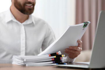 Man working with documents at wooden table in office, closeup