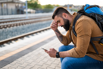 Obraz premium Adult man is sitting at railway station and waiting for arrival of train.