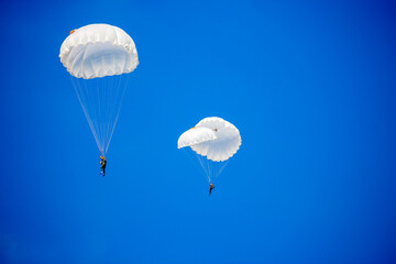 Skydiving. Flying parachutists against the background of the blue sky and mountains. Extreme sport and entertainment.