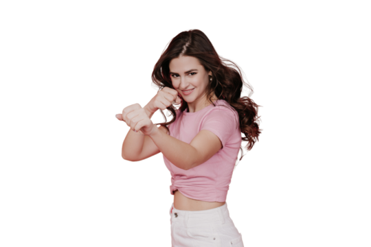 Fit brunette young woman in pink t-shirt and white pants practicing box, with clenched fists, looking at camera, toothy smiling transparent background with copy space. Sport, fitness, healthcare.