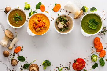 Mushroom and lentil cream soup, bean, carrot and tomato soup, broccoli and spinach soup on white background with cooking ingredients, copy space