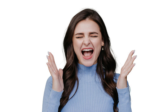 Loud screaming brunette angry girl in lilac sweater eyes closed with opened moth shouting rises hands up. Beautiful hispanic young woman annoyed, frustrated, scared over transparent background