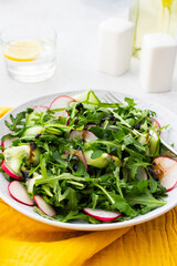 Healthy breakfasts, arugula and radish and cucumber salad with balsamic vinegar and olive oil, glass of water with lemon