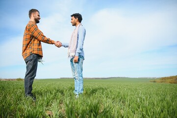 Obraz premium The concept of international relations in agrarian business. Indian and European farmers stand in a field of green wheat
