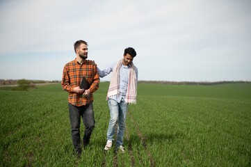 The concept of international relations in agrarian business. Indian and European farmers stand in a field of green wheat