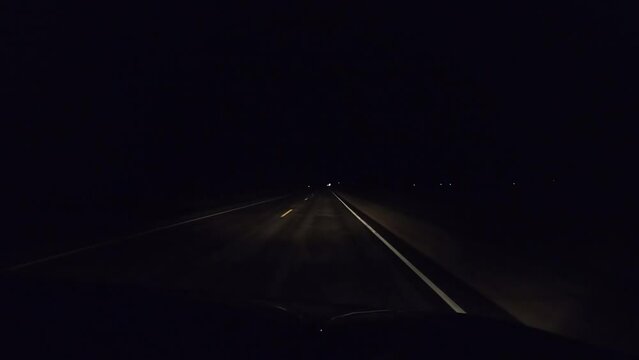 Dash camera view while driving slowly on country side road at night without any street lights.