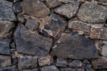 imagen detalle pared de piedras oscuras de distintos tamaños con algunas juntas 