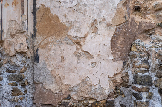 imagen detalle textura pared en mal estado con distintos colores y la pintura a trozos, la piedra del fondo queda visible 
