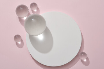 White round podium decorated with some glass balls on pastel pink background. Pedestal for cosmetic product and packaging mockups display presentation