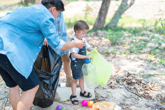 Asian family picking up trash in the forest. Litter cleanup activities. Environment protection. recycling.