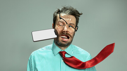 Fototapeta Expressive sad man, businessman in tie taking punch in face by flying smart phone. Concept of personal problems, financial loses, business fall obraz