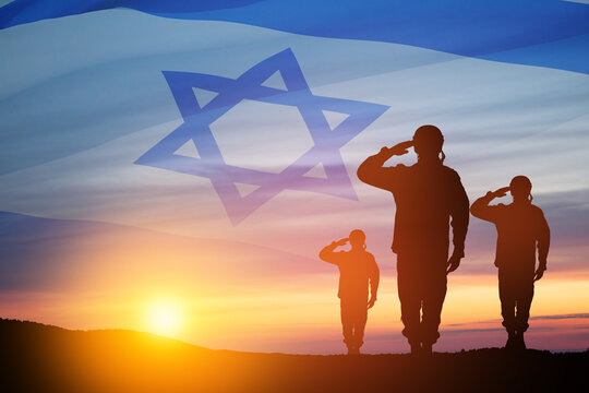 Silhouette of soldiers saluting against the sunrise in the desert and Israel flag.