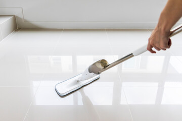 Housekeeper holding mop.Housewife cleaning floor.White floor with reflection.Close up of woman holding mop.Person wiping home.Female using spray mop in hospital or office.Mopping living room.