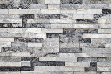 Wall background, lined with flat long granite tales of different shades of gray, uniform texture