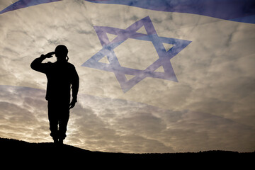 Silhouette of soldier saluting against the sunrise in the desert and Israel flag.