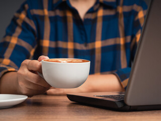 Man in a shirt holding a cup of coffee while sitting at the table