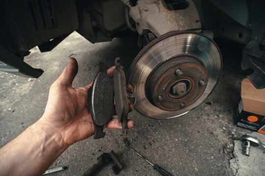 Disk brake and car service concept - Vehicle brake pad replacement service by hand of mechanic man in car, do it yourself, myself. Old and new pards.