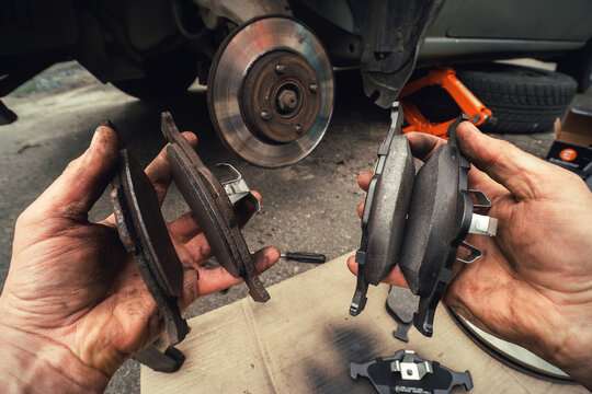 Disk brake and car service concept - Vehicle brake pad replacement service by hand of mechanic man in car, do it yourself, myself. Old and new pards.