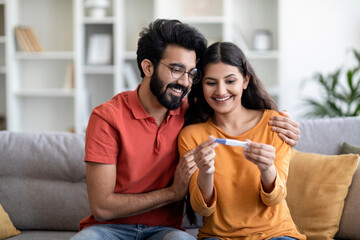 Fototapeta Portrait Of Happy Young Indian Couple Holding Positive Pregnancy Test At Home Generative AI obraz
