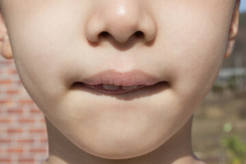 This is the face of an Asian child with tightly closed lips.