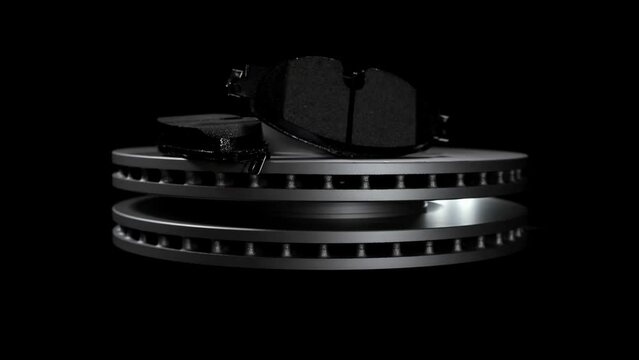 New disc brakes and ceramic pads. Set of car spare parts for repair and replacement on wheels. Pair of rotor braking disks. Clean vehicle metallic equipment details for auto transport isolated in dark
