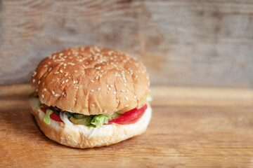 big beef burger with buns with sesame seeds on wooden background, close up