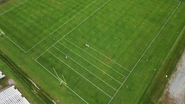 Aerial overhead shot of crew painting lines on grass football field during summer.