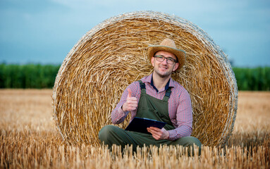 Naklejka na ściany i meble Happy farmer in a wheat field after the harvest. Agricultural concept