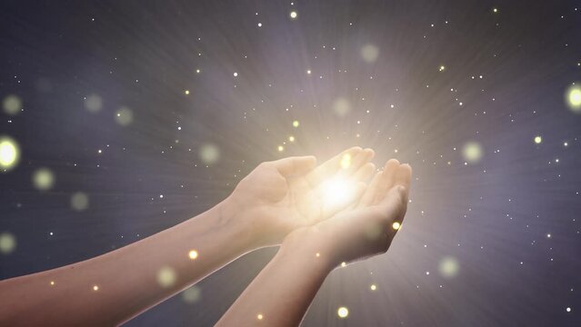 Conceptual Visualization Of Male Or Female Hands Reaching Out In Prayer On Magical Dark Blue Background. Person Connecting With Higher Spiritual Energy Through Bright Light In Their Palms.