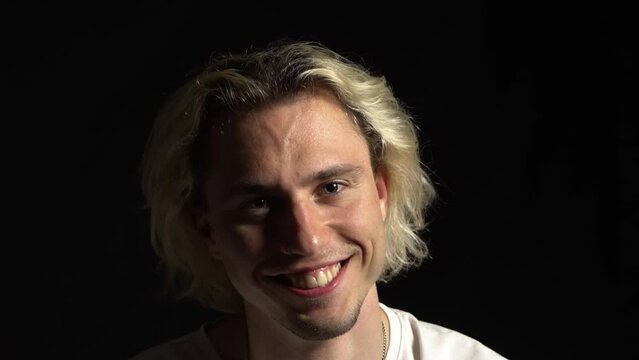 A young blond man madly smiling like a joker