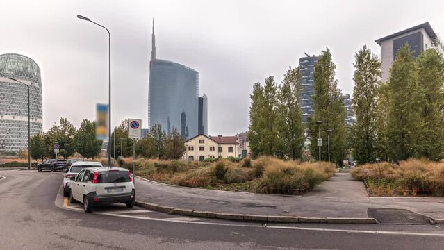 Panorama showing skyscrapers and towers from park with outumn treea and green lawn timelapse. Located between Piazza Gae Aulenti and the Isola district. Traffic on a road. Milan. Italy