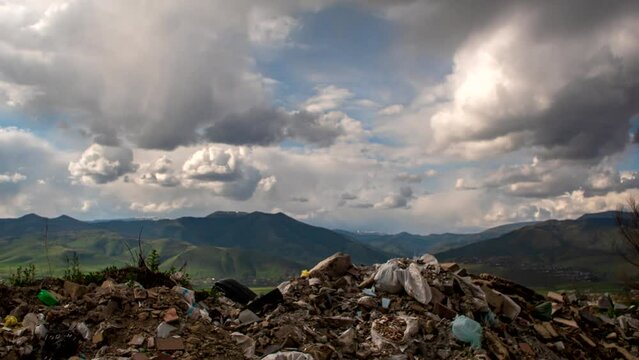 time lapse A lot of piles of abandoned garbage and waste in the mountains with beautiful scenery and fast moving clouds. The concept of ecology pollution and the problem of a spontaneous garbage dump